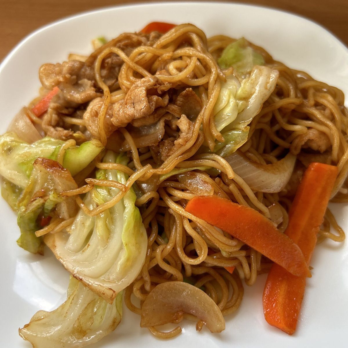 Plate of yakisoba noodles with cabbage, carrots, and meat in brown sauce