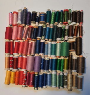 Rows of colorful sewing thread spools arranged on a white background