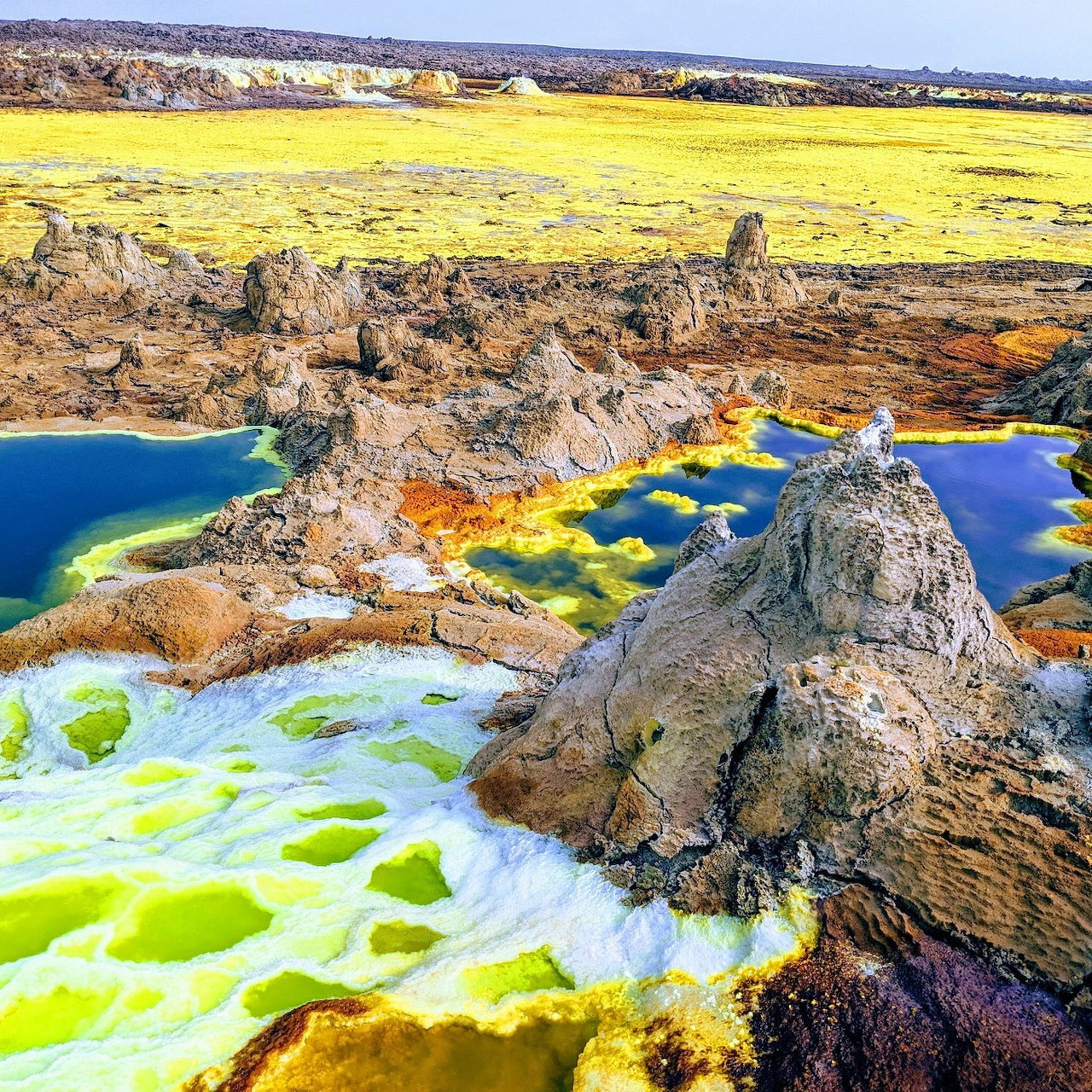 Colorful geothermal pools and rocky formations in a bright mineral landscape