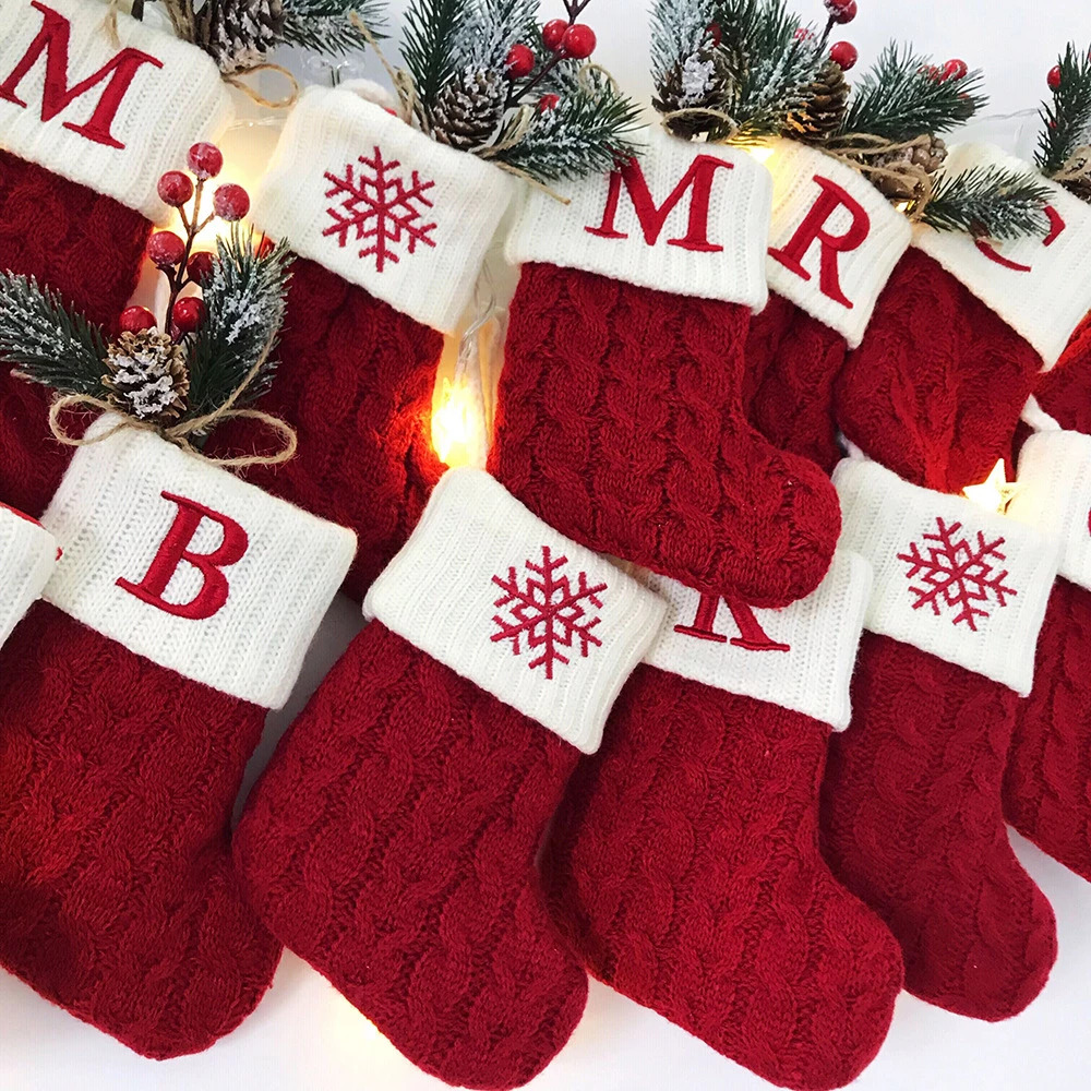 Red knit Christmas stockings on banner with letters and snowflakes, decorated with pine garland