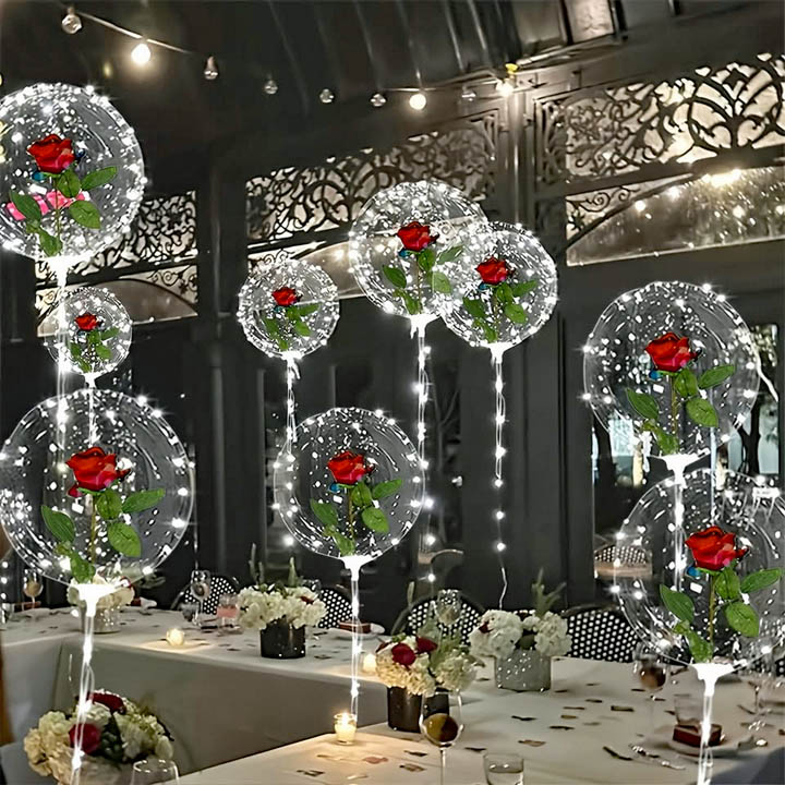 Illuminated white sphere Christmas ornaments with red flowers hanging in decorated indoor venue