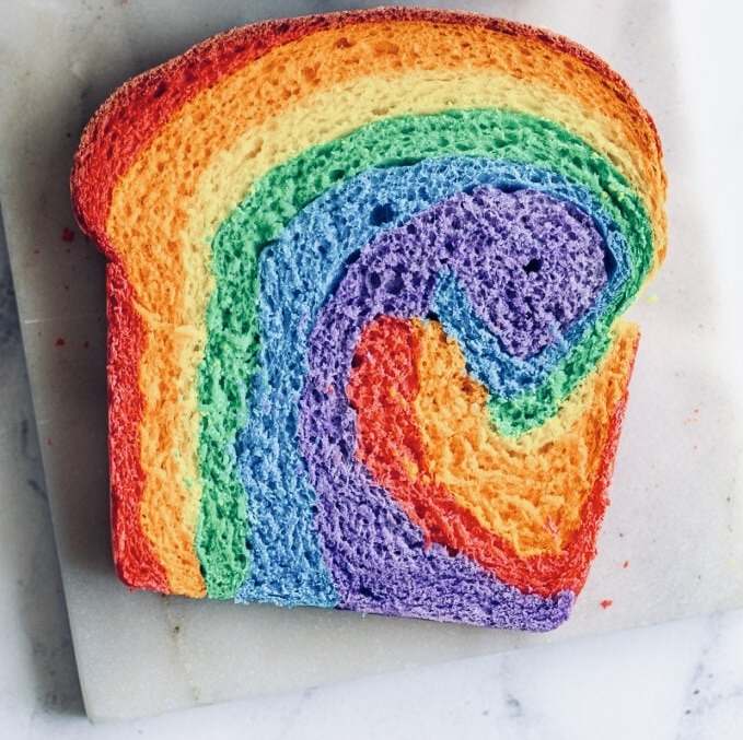 Single slice of bread with colorful rainbow swirl pattern on white surface