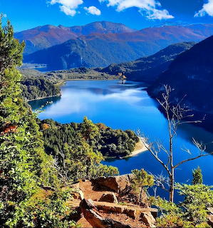 Blue mountain lake surrounded by green hills and mountains under a clear sky