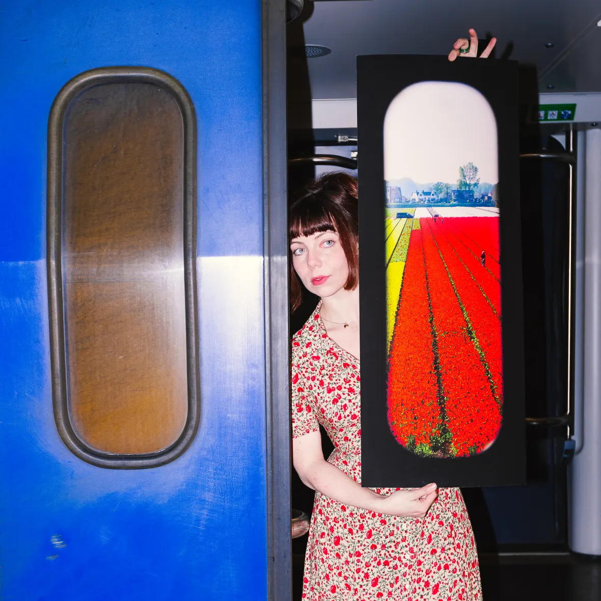 Woman in floral dress standing between blue train doors at station platform