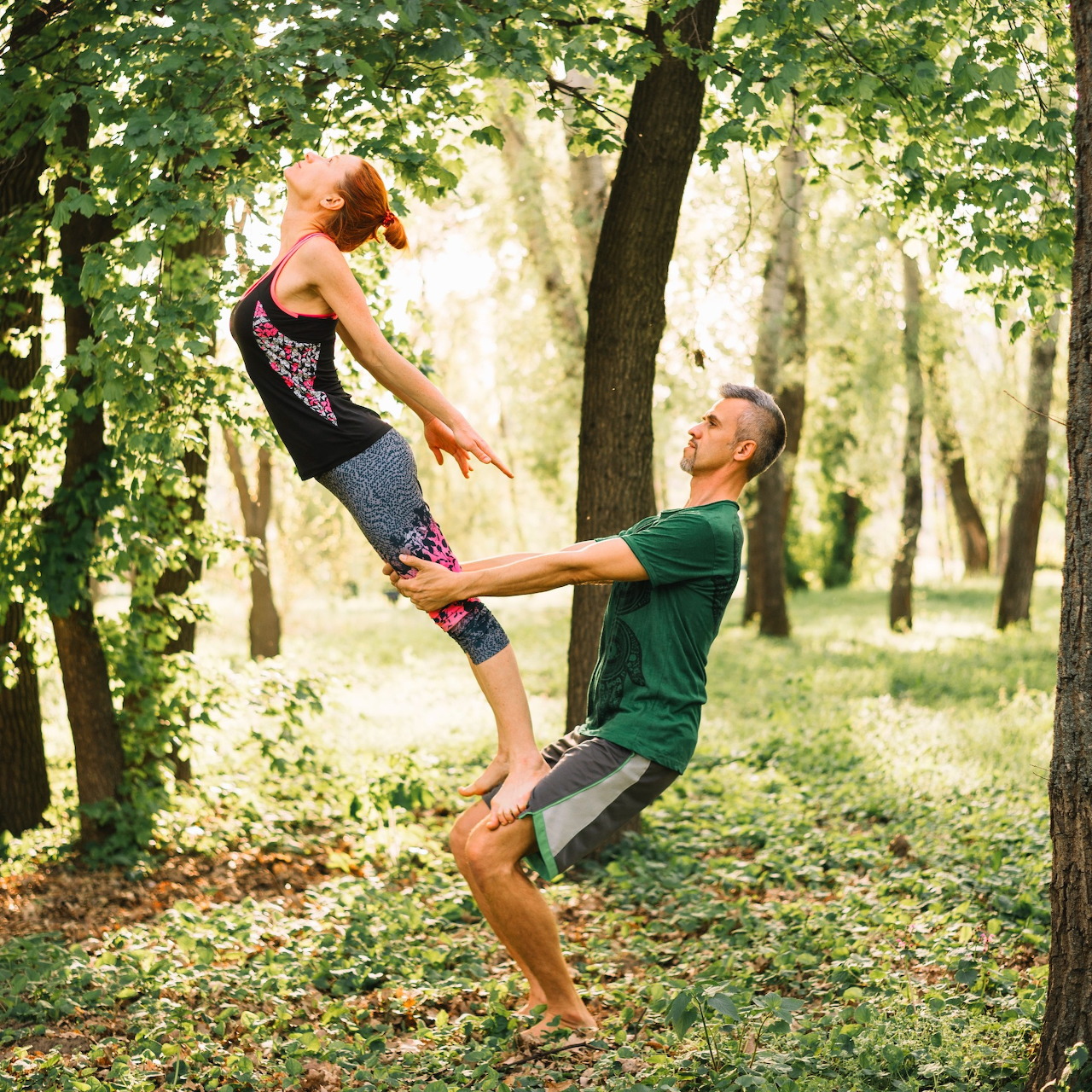 Man and woman doing an acrobatic dance pose in a wooded park