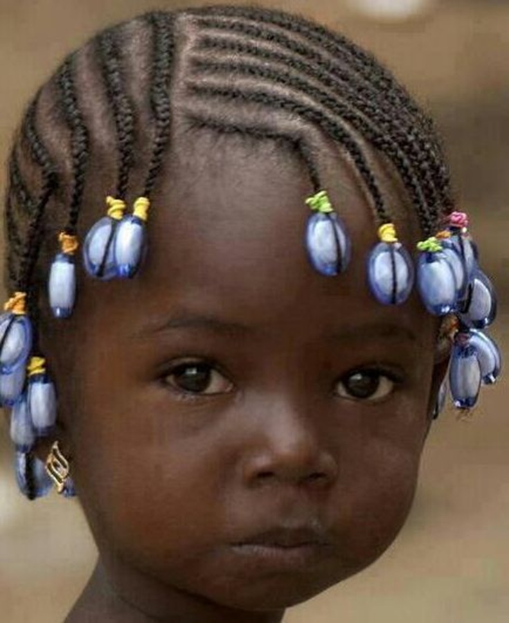 Close-up of a young girl with braided hair and blue beads