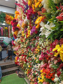 Multi-colored artificial flower wall with roses, lilies and various blooms arranged in vibrant rainbow pattern