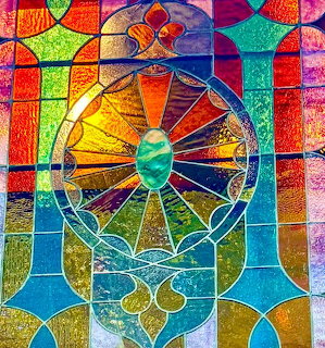 Colorful stained glass window with geometric patterns and circular mandala design in rainbow colors
