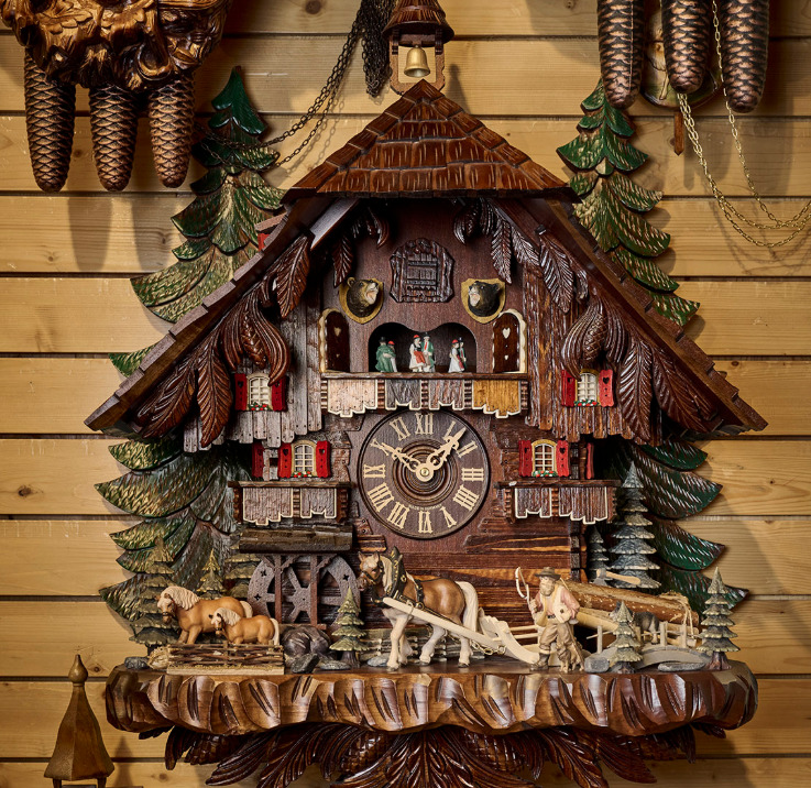 Carved wooden German cuckoo clock with chalet roof, pine trees, and deer figures