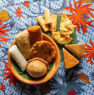 Assorted Indonesian fried snacks and appetizers on orange plate with banana leaf over blue batik cloth