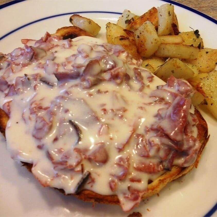 Creamed chipped beef on toast with hash brown potatoes on a white plate