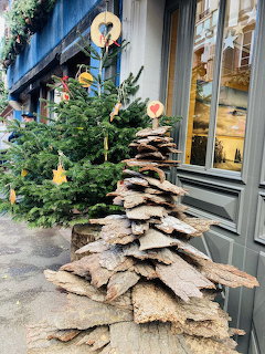 Christmas tree with heart ornaments and a stacked stone slab tree sculpture outside a shop in Ribeauville