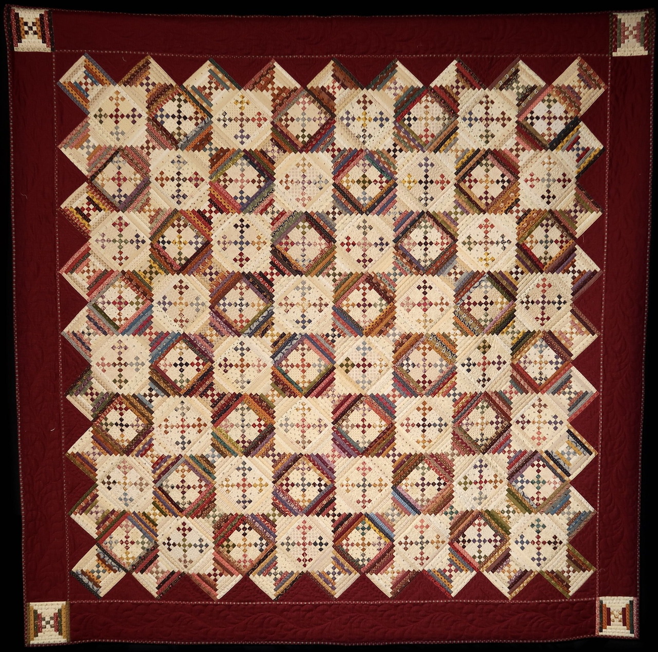 Geometric quilt with red border and repeating courthouse steps pattern in red, cream, and brown blocks