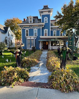 Blue Victorian inn with Halloween decorations and an autumn garden along the front walkway