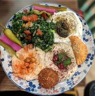 Overhead view of a Lebanese lunch plate with hummus, tabbouleh, falafel, and pita bread