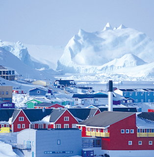 Colorful houses in Ilulissat Greenland with large icebergs in the background