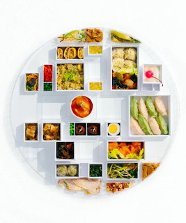 Round white sectioned platter with multiple compartments containing assorted gourmet foods and sauces