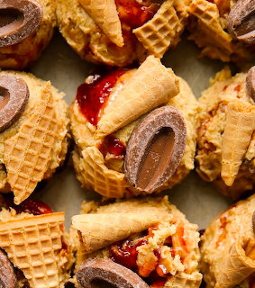 Dessert bites with mini waffle cones, red jam and chocolate on parchment