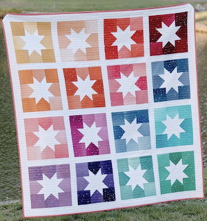 Colorful quilt with 16 white star blocks arranged in grid on rainbow colored backgrounds