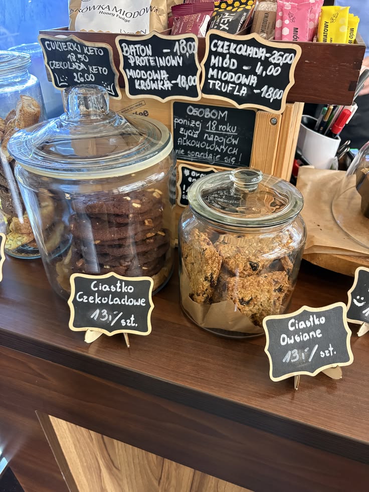 Glass jars of cookies and pastries on a wooden cafe counter with chalkboard labels
