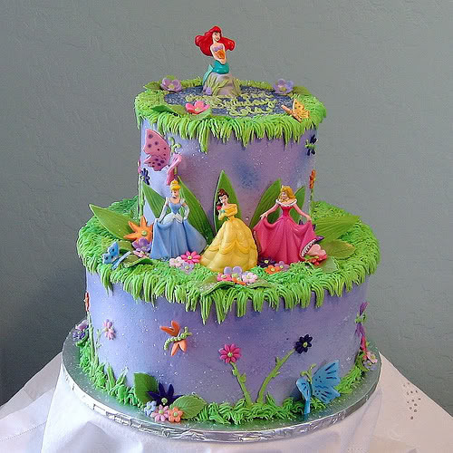 Purple two-tier cake with Disney princess figures and green grass frosting decoration