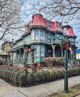 Ornate Victorian house with teal siding, red roof, and Christmas decorations on a street corner