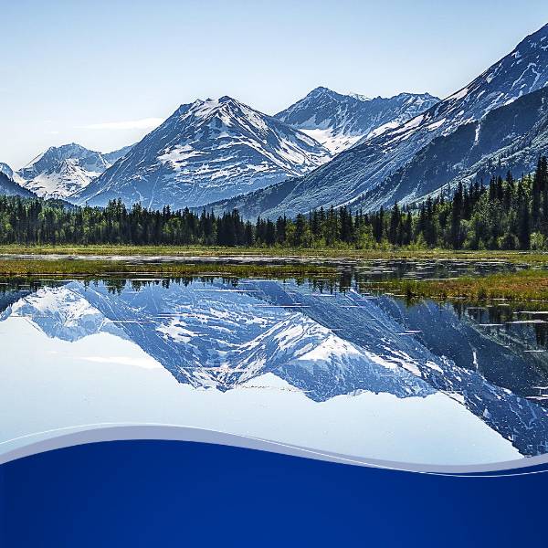 Snow-covered mountains reflected in still alpine lake with forest
