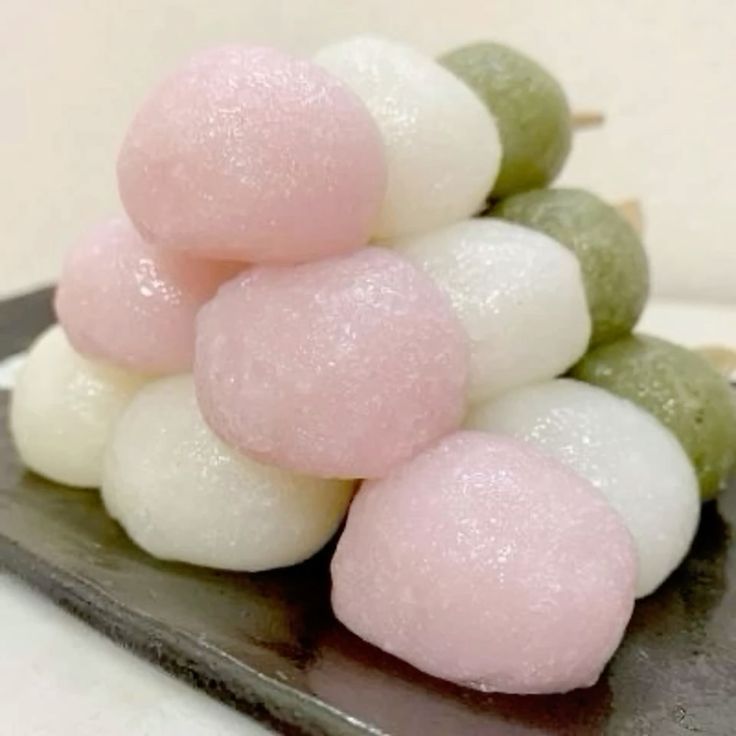 Close-up of pink, white, and green dango rice dumplings stacked on a dark plate