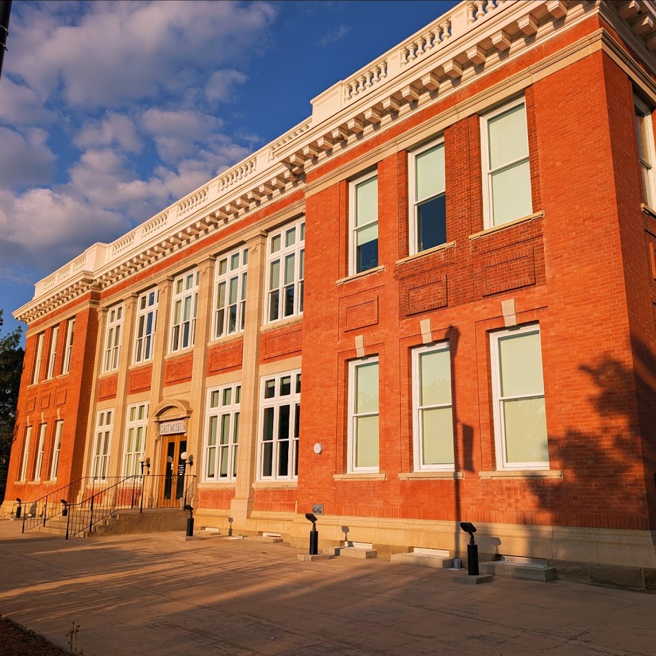 Red brick historic museum building with white columned entrance and multiple windows