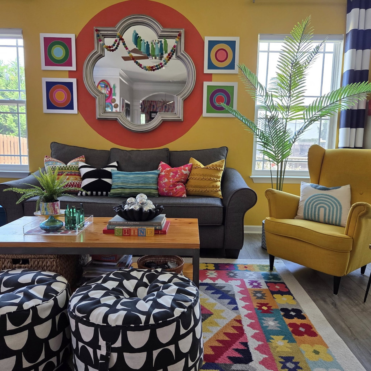 Bright maximalist living room with colorful geometric rug, teal sofa, yellow armchair, and bold wall art