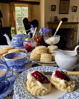British cream tea with scones, clotted cream, jam, and blue and white china on a cottage table