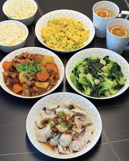 Multiple white bowls and plates with Chinese dishes including rice, vegetables, and meat arranged on dark surface