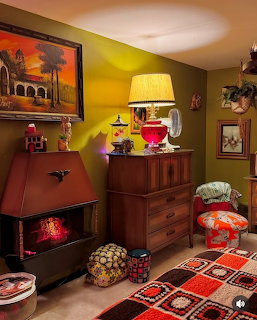 Retro 1970s living room with red fireplace stove, wooden dresser, colorful lamps, and crocheted blanket
