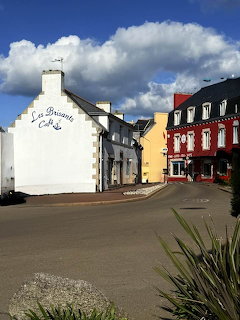 Colorful village street in Treffiagat, Finistère, with white café building and Breton houses under blue sky