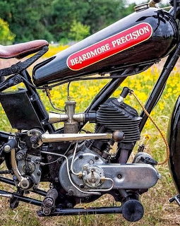 Close-up of 1924 Beardmore Precision vintage motorcycle showing engine, frame, and red tank badge with leather seat