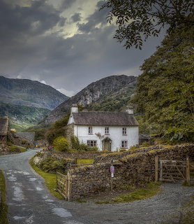 White cottage on rural road with mountains and stormy sky in British countryside