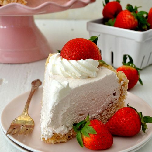 Slice of strawberry cream pie with whipped topping and fresh strawberry on white plate