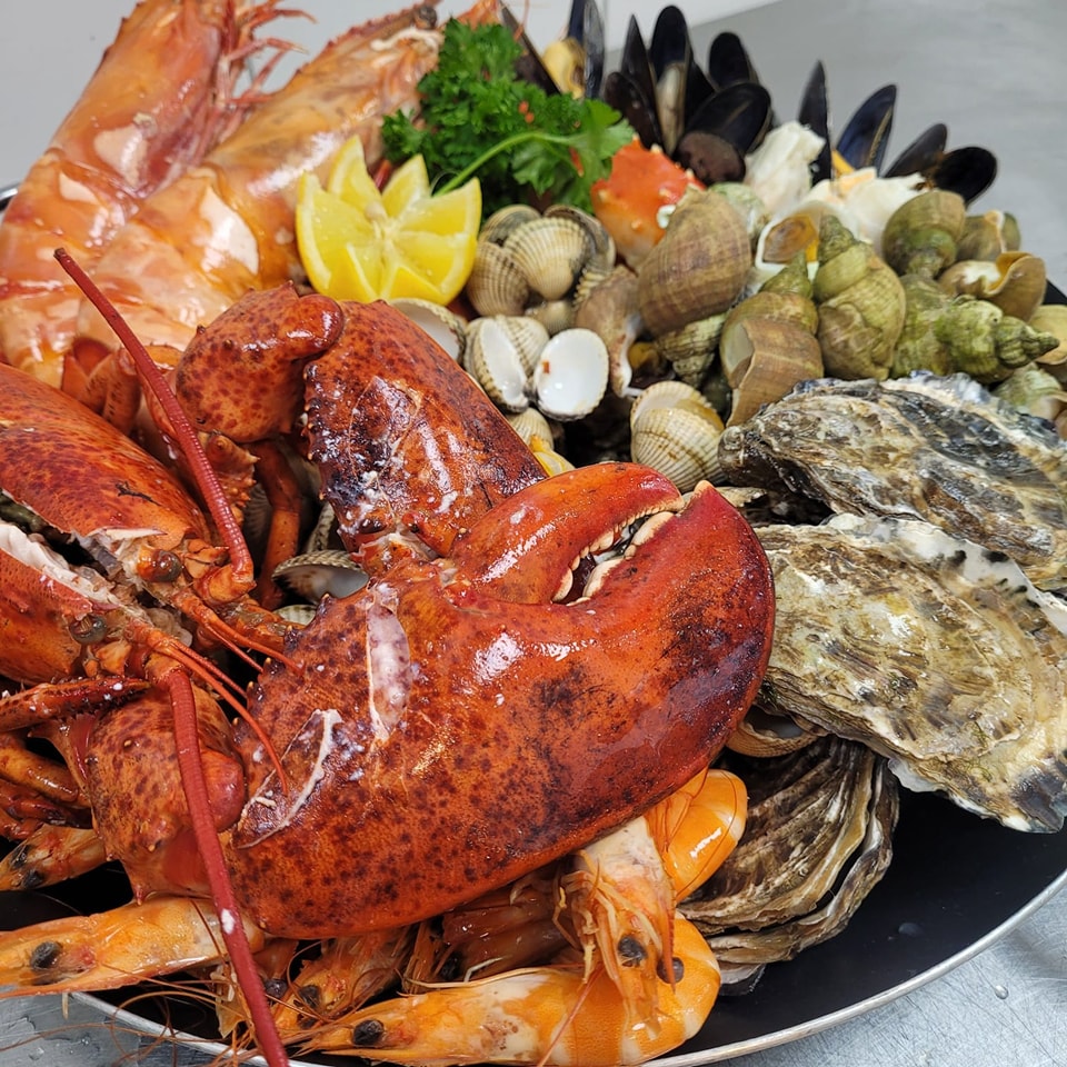 Close-up seafood platter with lobster, shrimp, oysters, mussels, clams, lemon, and parsley
