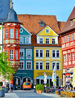 Row of bright colored historic German buildings with terracotta roofs and tower spire in town square