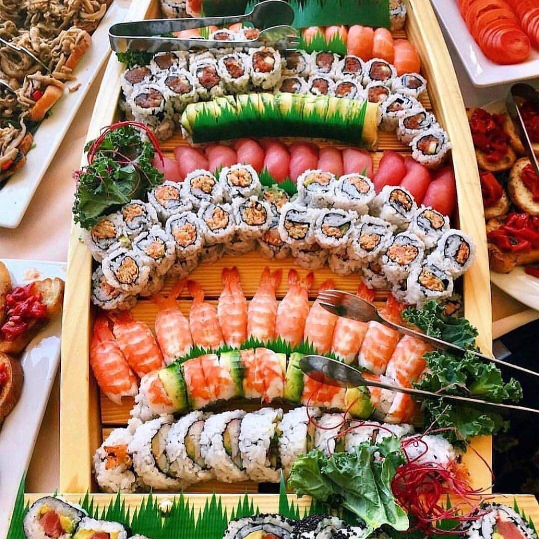 Overhead view of colorful sushi platter with assorted rolls and nigiri arranged in rows on wooden boat