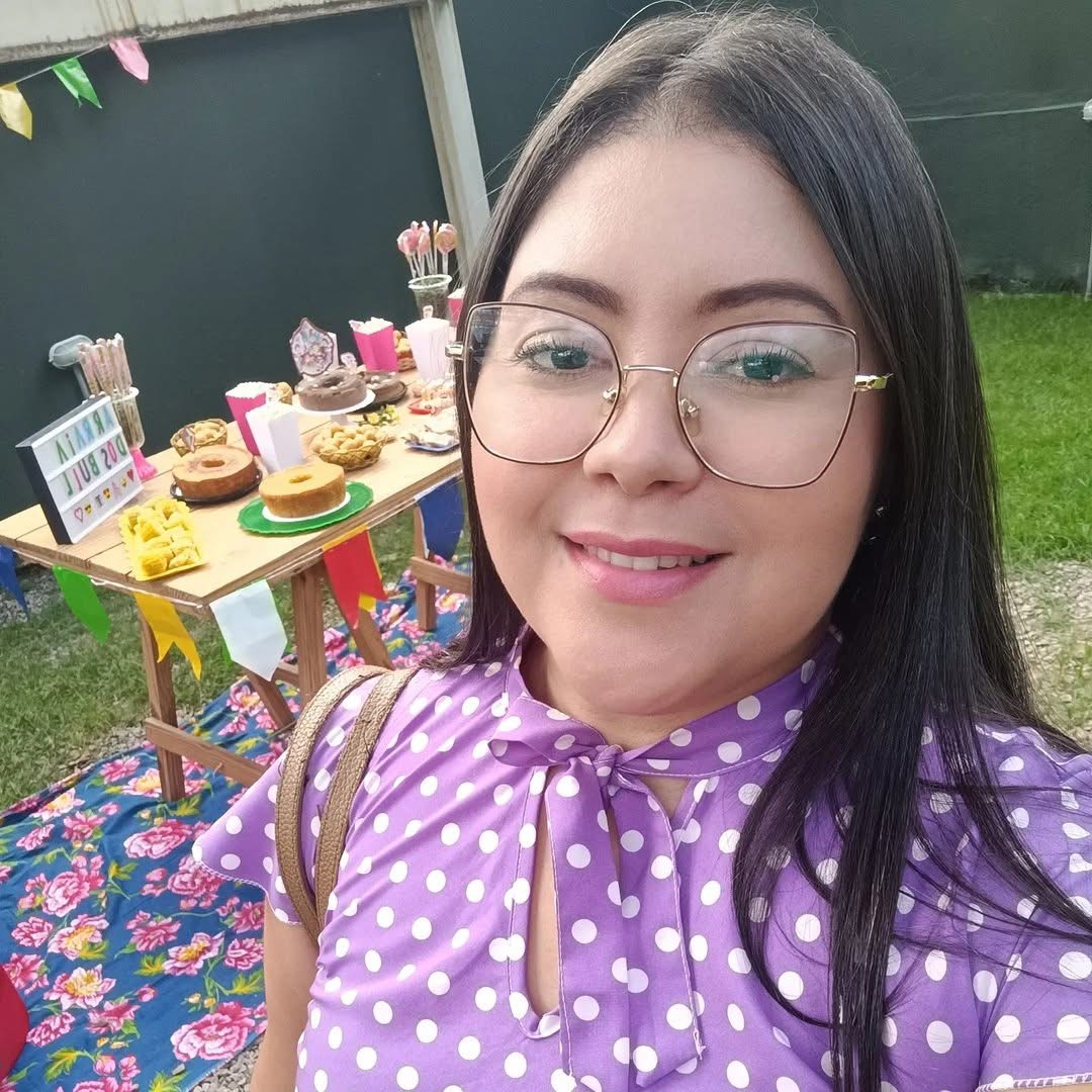 Smiling woman in glasses taking an outdoor selfie beside a decorated table