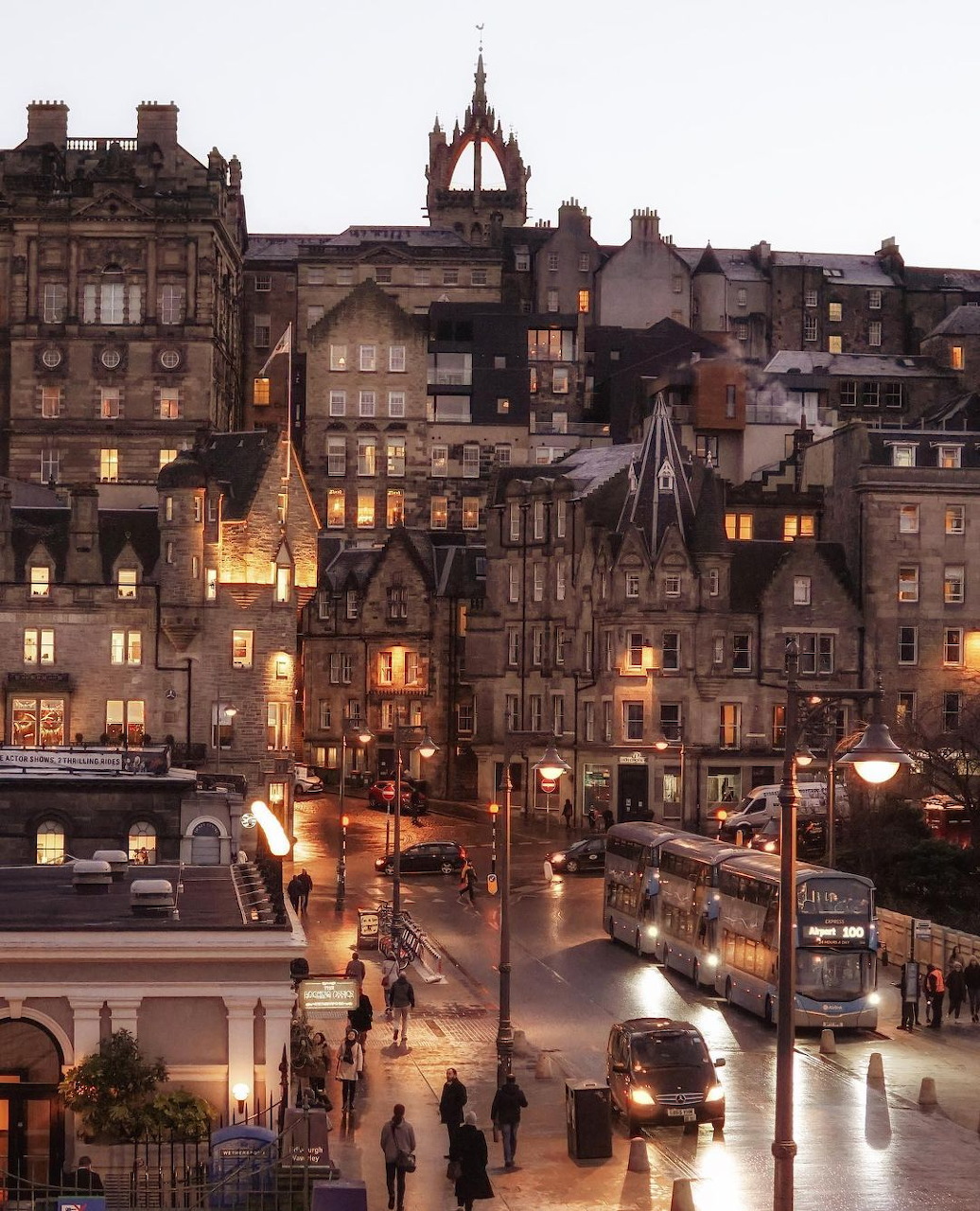 Edinburgh Old Town historic buildings lit up at dusk with street traffic and glowing windows