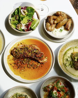 Assorted Mediterranean dishes in white bowls from above including hummus, salad, and grilled chicken