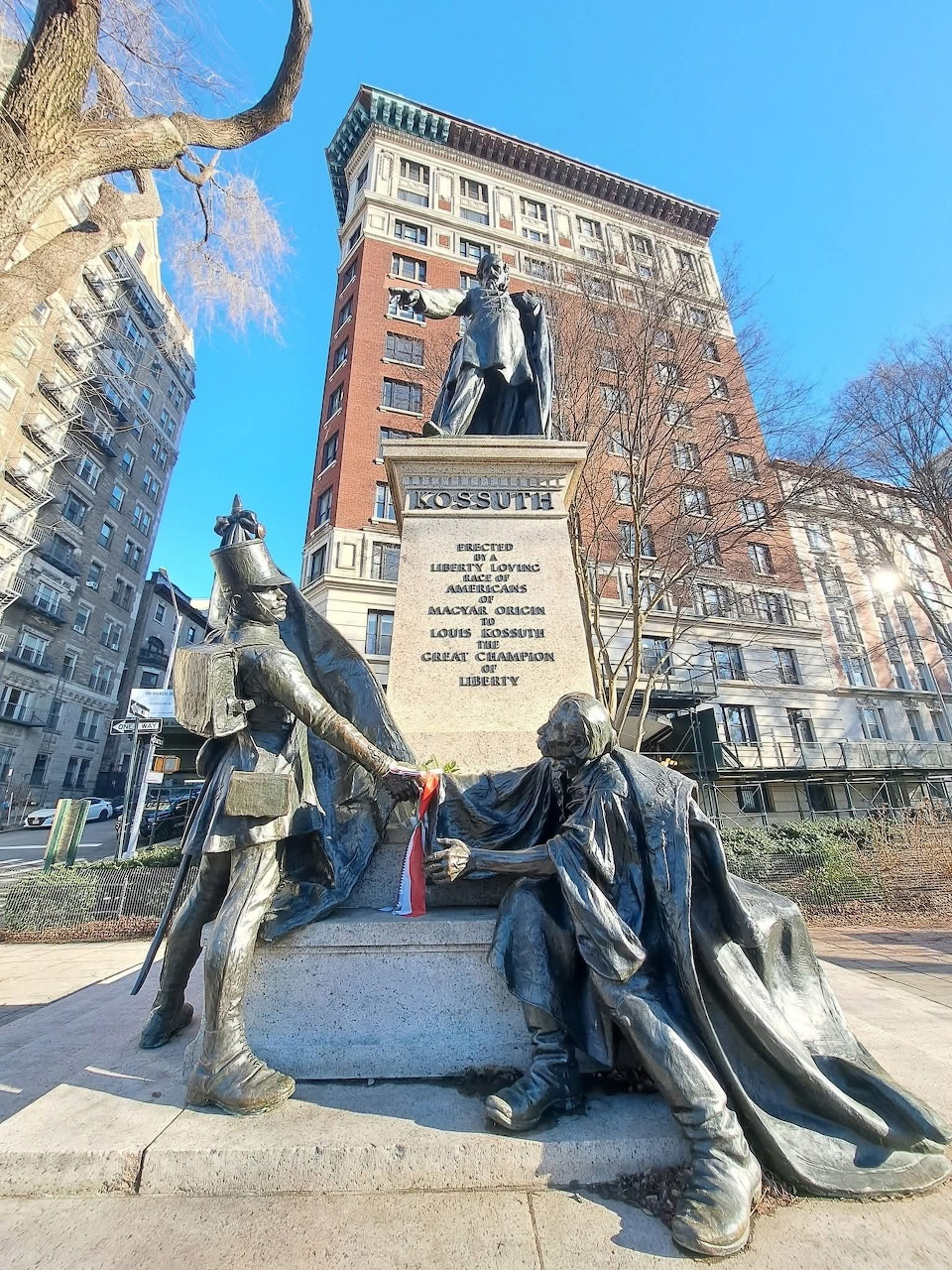 Bronze statue of Kossuth on stone pedestal with allegorical figures in Manhattan urban park