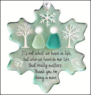 Snowflake-shaped Christmas ornament with trees, birds, and a quote on a pale green background