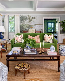 Elegant living room with green sofa, floral pillows, dark wood coffee table, and blue-white decor