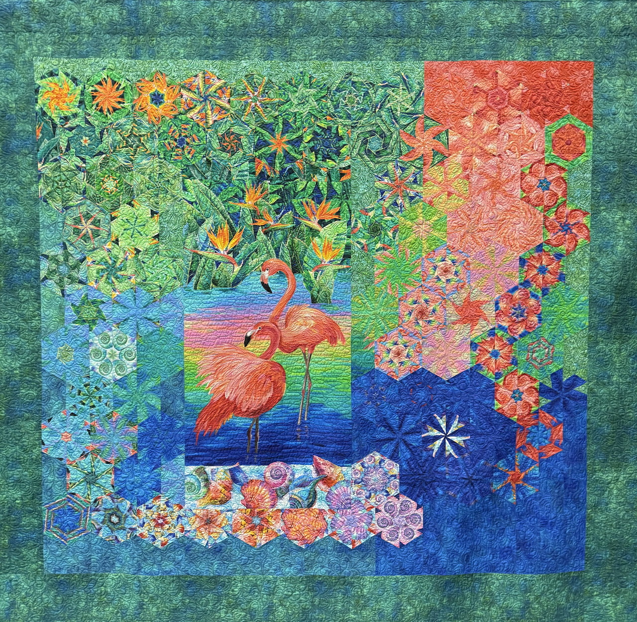 Decorative quilt with pink flamingo centerpiece amid colorful floral and leaf fabric patches in blue, green, and coral tones