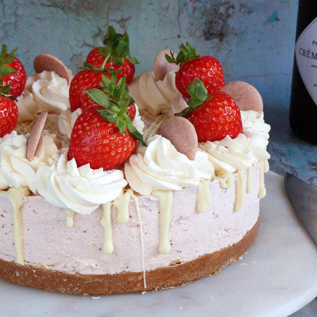 Strawberry cheesecake topped with fresh strawberries, whipped cream swirls, white chocolate, and chocolate truffles