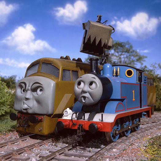 Thomas the Tank Engine and a diesel train on tracks beneath a blue sky