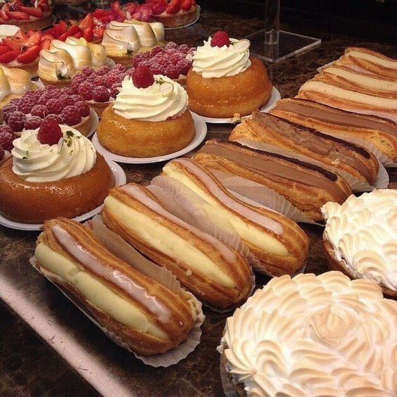 Assorted pastries with cream, berries, and glazes arranged on trays